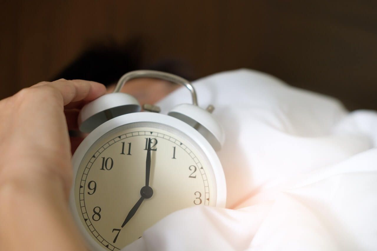 Czego chcę od tego dnia - narzędzie rozwojowe - mężczyzna w łóżku wyłączający budzik